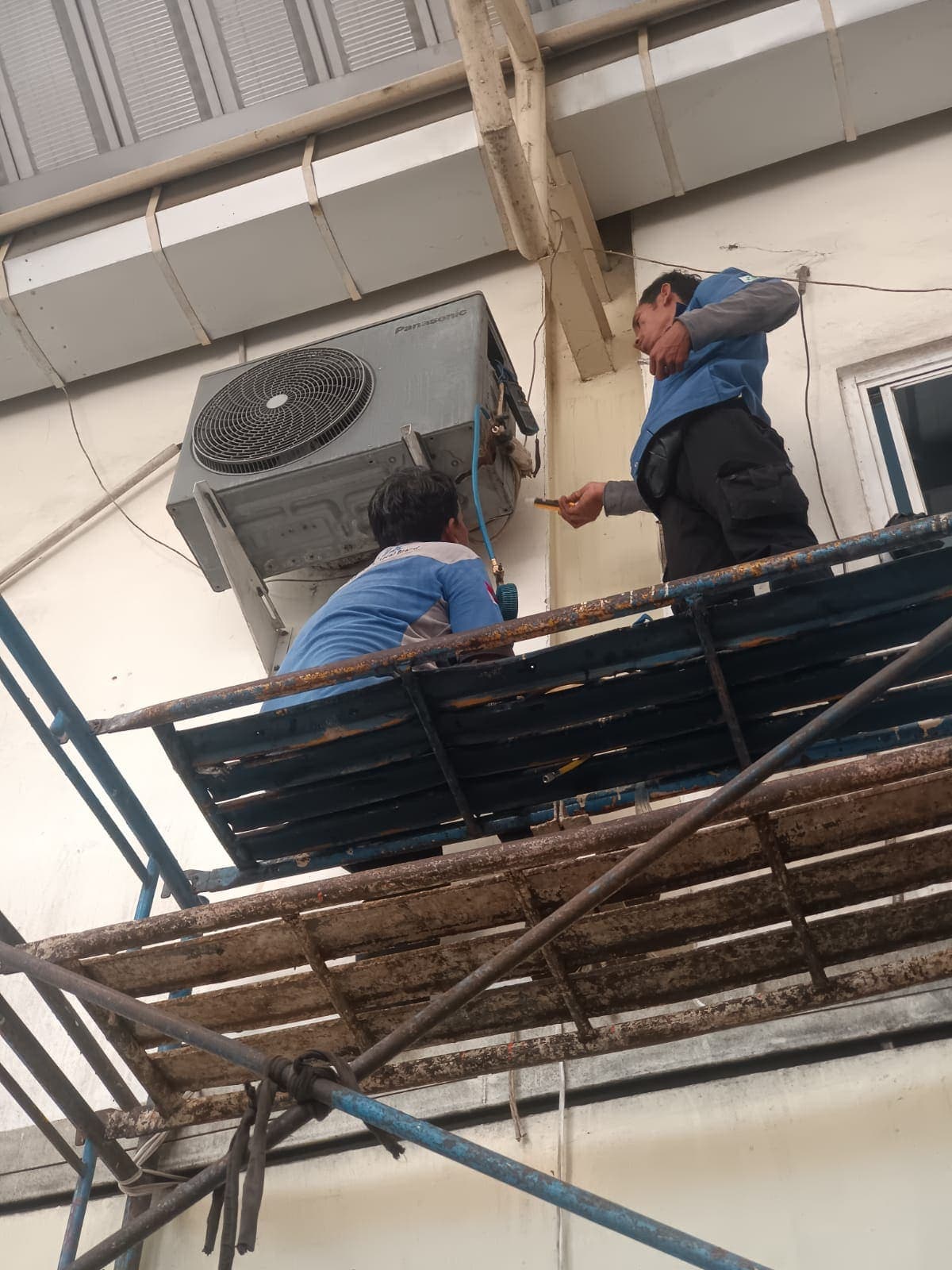 Teknisi Mukundo Teknologi Indonesia melakukan servis AC pada unit outdoor di lokasi pelanggan